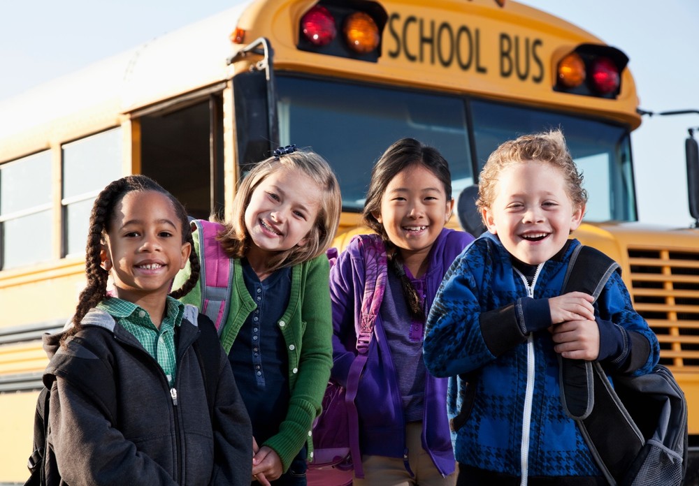 4 students standing in front of school bus