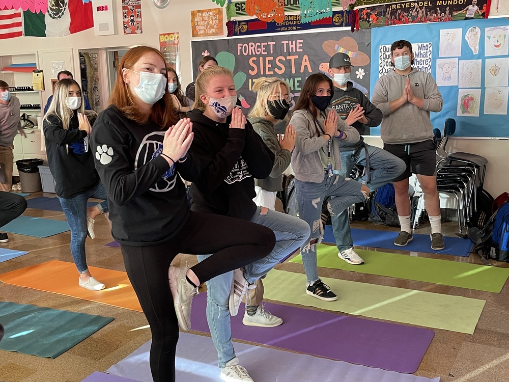 Students in a classroom doing a yoga pose.