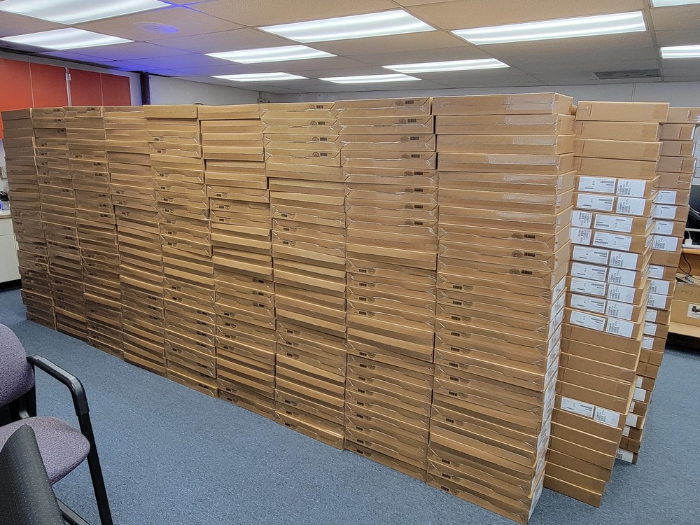 Photo of 1,000 chromebooks in boxes stacked in an office