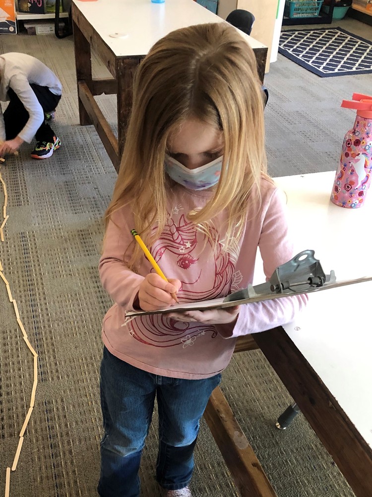 Kindergartner writing on a clipboard