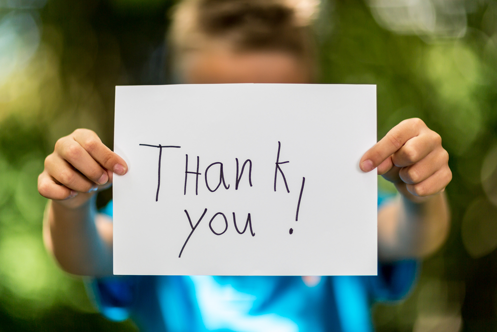Child holding up "Thank you!" sign