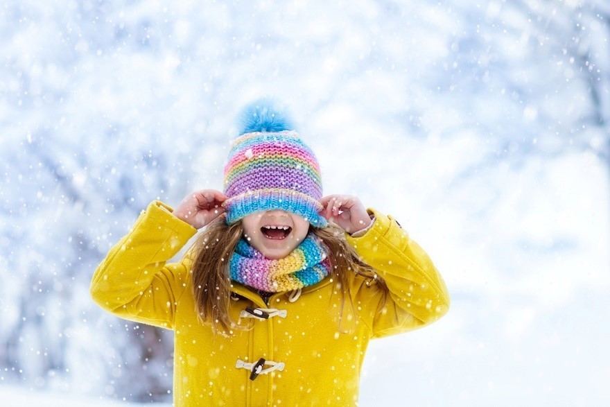snowy winter scene with a girl in a yellow jacket, hat and scarf